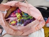a pink bag full of little pony figurines sitting on a table