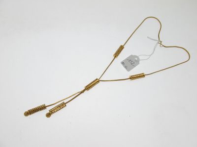 gros plan d'un collier en or sur une surface blanche