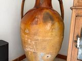 a large brown vase sitting next to a wooden cabinet