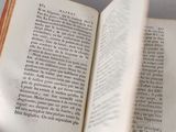 someone is reading a book on a table with a white table cloth
