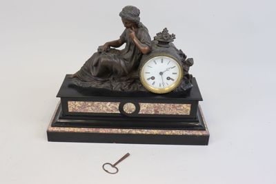 une statue de femme assise sur une table avec une horloge