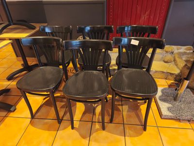 quatre chaises noires posées sur un sol carrelé dans une pièce