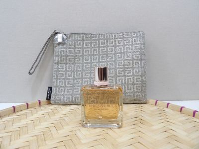 a bottle of perfume sitting on a table next to a purse
