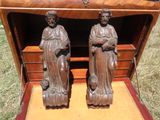 paire de statues anciennes en bois représentant deux hommes, rangées dans un coffre
