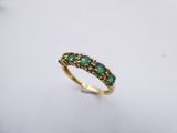 a close up of a gold ring with green stones