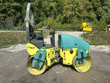 a yellow and blue road roller sitting on top of a gravel road
