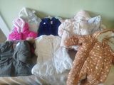 a pile of baby clothes on a bed in a room