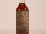 an old bottle of whiskey sitting on top of a white table
