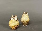 two small gold birds are sitting on a gray surface