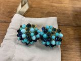 une paire de boucles d'oreilles bleues et vertes posées sur un tissu blanc