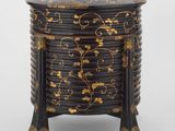 une image représentant une boîte en bois décorée de noir et d'or, posée sur un socle