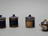 three small blue and gold containers are sitting on a white surface