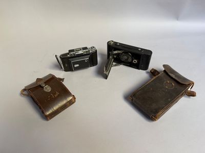 Plusieurs vieux appareils photo sont posés les uns à côté des autres sur une surface blanche