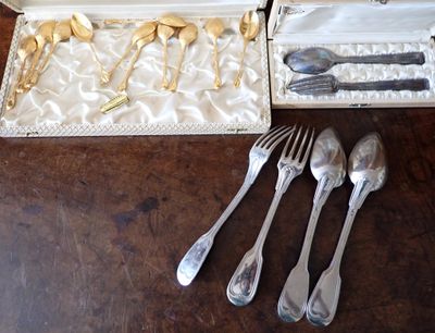 des couverts dans une boîte posée sur une table, à côté d'autres couverts