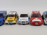 five toy cars lined up in a row on a white surface