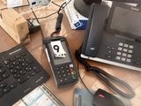 a desk with a computer, phone, and other electronics on it