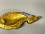 a gold plate with a fish on it on a white surface