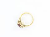 a close up of a gold ring with a red stone