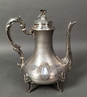 an antique silver tea pot with a bird on top of it