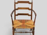 une vieille chaise en bois dont l'assise est jaune et rouge sur fond gris