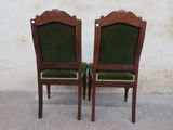pair of green upholstered chairs in front of a white wall