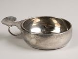 a silver bowl with a handle on a white surface