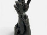 une statue noire représentant une main levant un doigt