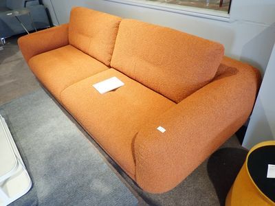 un canapé orange dans une pièce où est accroché un tableau au mur