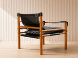 La chaise est en bois et son assise est en cuir noir.