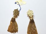 une paire de boucles d'oreilles en or ornées de pompons sur fond blanc