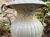 a large vase sitting on the ground in front of a stone wall