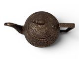 an old cast iron teapot with a handle on a white surface