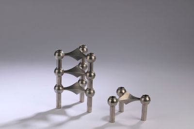 three pieces of metal on a white surface with a gray background