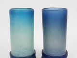 deux vases en verre bleu posés l'un à côté de l'autre sur une surface blanche