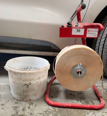 une voiture blanche garée à côté d'un seau blanc et d'un tuyau d'arrosage rouge