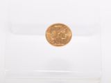 a gold coin in a clear plastic box on a white surface