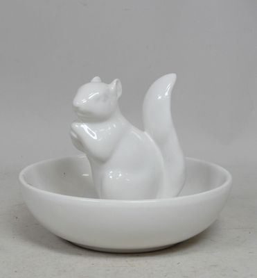 a white cat figurine in a bowl on a table