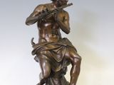 statue en bronze représentant un homme jouant de la flûte, posée sur un socle en marbre
