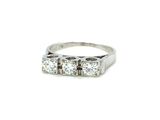 a close up of a three stone diamond ring on a white background