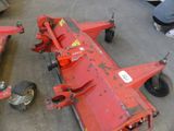 two red farm implements sitting on the floor in a warehouse