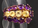 un gros plan d'une bague ornée de pierres violettes et jaunes