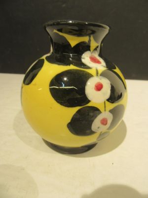 a yellow vase with black and white flowers on it