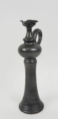 un vase noir posé sur une surface blanche
