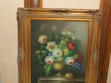 une photo d'un tableau posé par terre à côté d'un vase de fleurs
