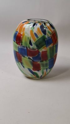 un vase en verre multicolore posé sur une surface blanche