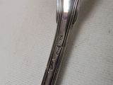 a silver spoon with a handle on a white surface