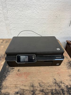 an hp printer sitting on top of a wooden table next to a white wall