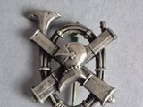 a silver brooch with a hammer and a wrench on it