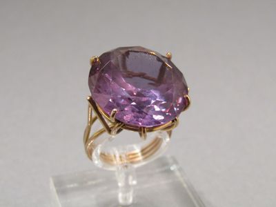 an image of a ring with a purple stone on a clear stand