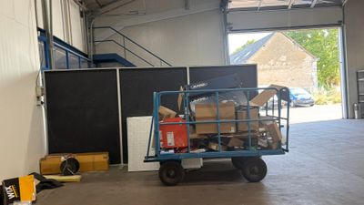 un chariot rempli de cartons dans un entrepôt dont la porte est ouverte
